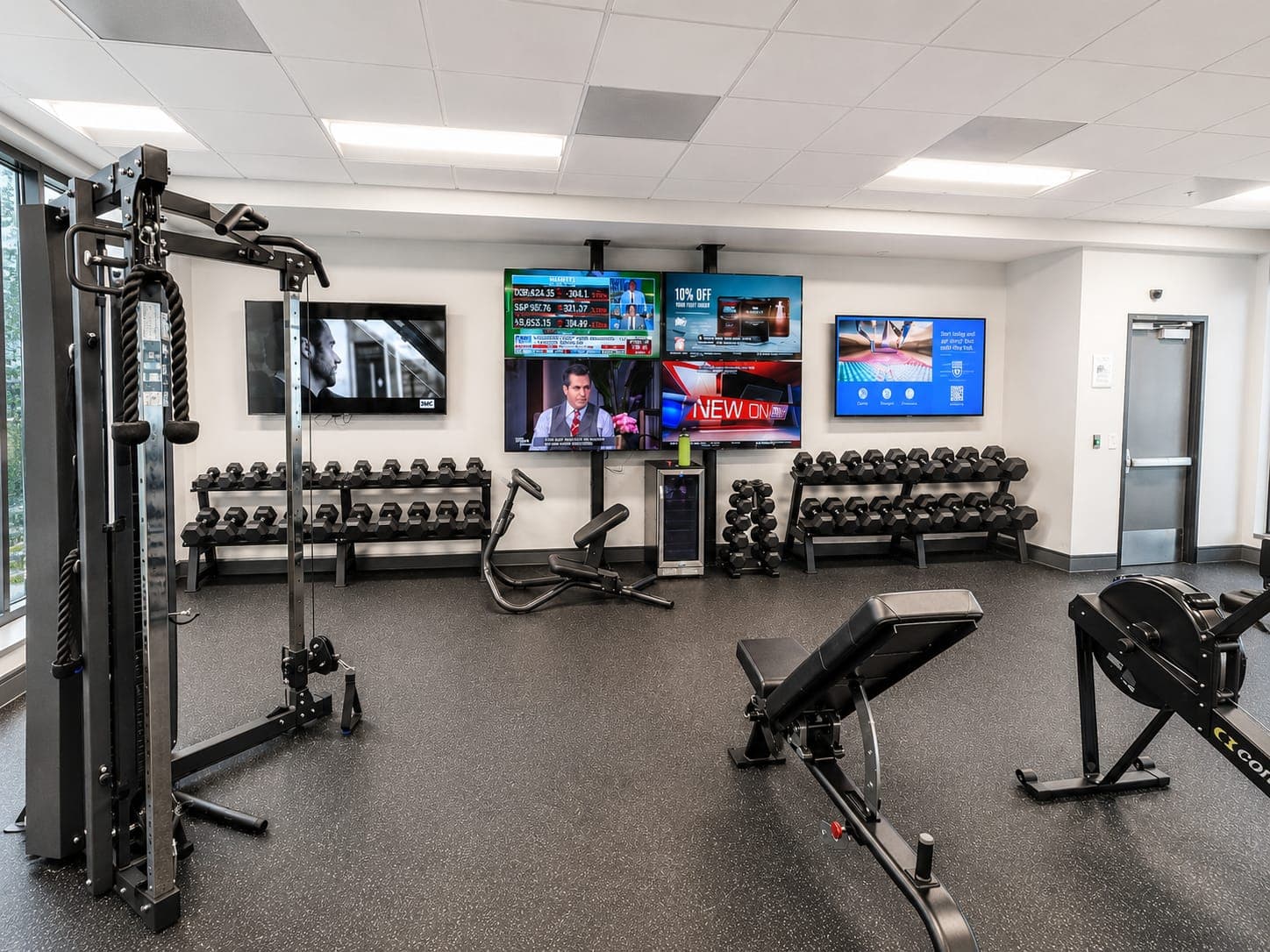The second-floor fitness center at 200 EVB: free weights, cable machines and cardio equipment under daylight